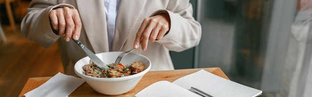 Close up of businesswoman is having a business lunch during working day in cafe blurred background