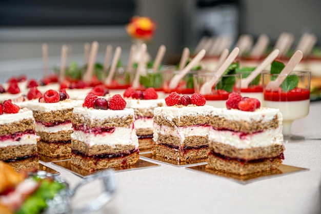 Close up of cakes with fresh fruits and berries arranged in a row on a party table