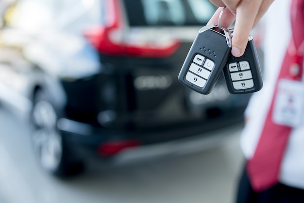 Close-up of a car key - a young man holding a new car key in the car showroom, new key