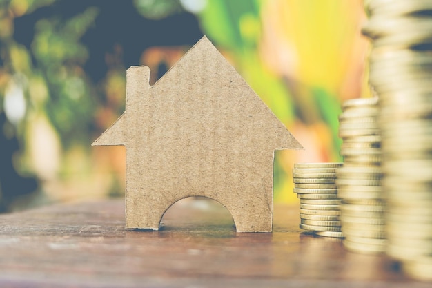 Close-up of cardboard model home by stacked coins on table