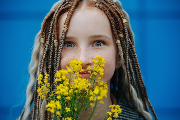 Close up of a carefree teenage girl looking at camera holding yellow flowers