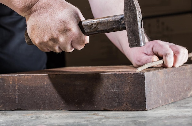 Photo close-up of carpenter hammering metal