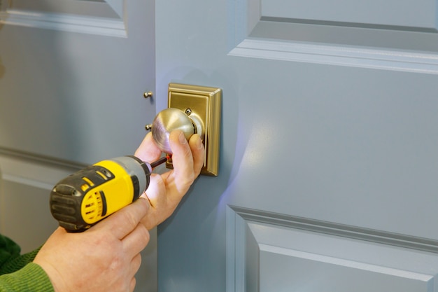 Close-up carpenter hands with doorlock during lock process installation