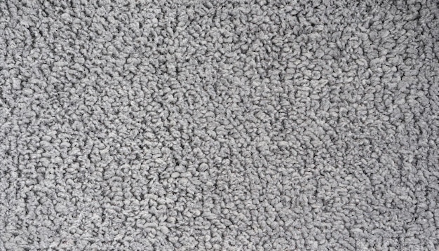 A close up of a carpet that is grey and has a white background.