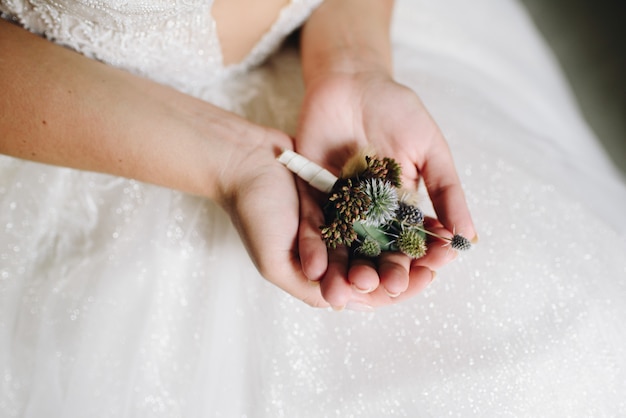 Close up of caucasian bride holding a delicate flower boutonniere on the day of her wedding