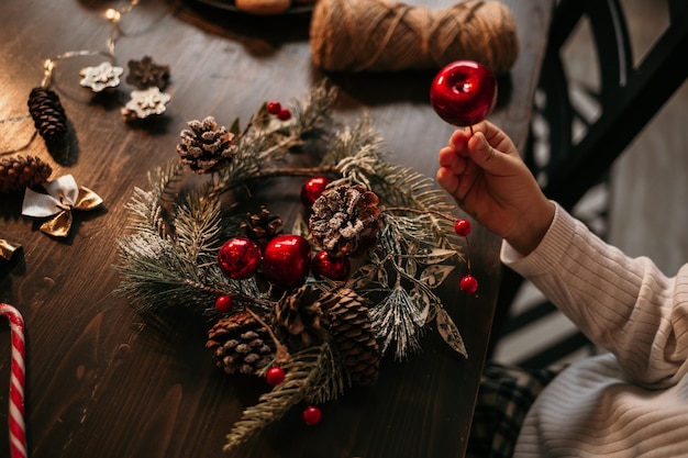 Close-up of a Caucasian child sitting at a table and making a Christmas tree wreath