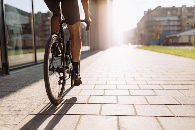 Close up of caucasian man with muscular legs riding sport bike during sunny day outdoors Urban area for training Healthy and active lifestyles concept