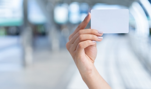 close up caucasian woman hand holding blank white business card on blurred corridor path background for  ,show, promote content and message 