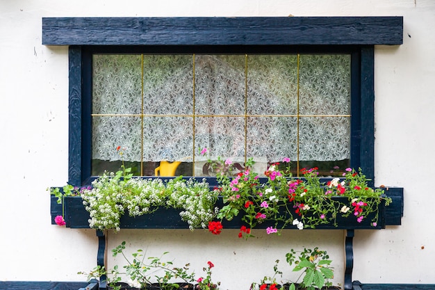 Close up of a charming window of a white old house and flowers