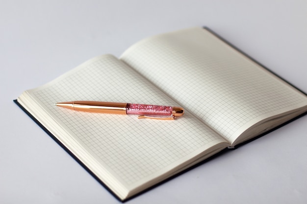 Close-up of checkered notebook with golden pink brilliant pen