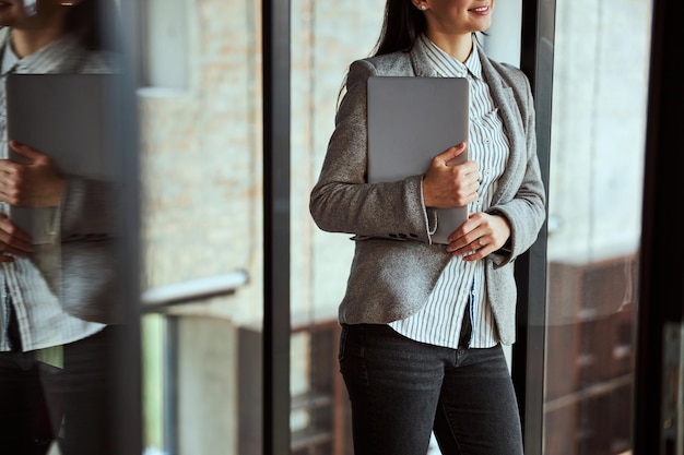 Close up of cheerful lady standing near glass wall