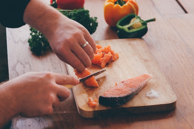 Close up chef cuting salmon on wooden borad.