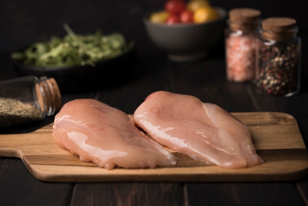 Close-up chicken breast on wooden board with ingredients