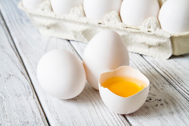 Close-up of chicken eggs and egg yolk on light wood