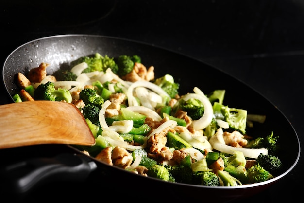 A close-up of chicken with vegetables on a frying pan