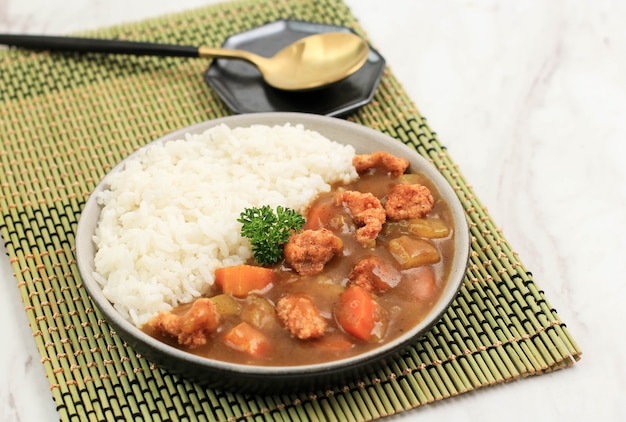 Close Up ChickenCrispy with Japanese Curry, Serve with White Rice on Black Ceramic Plate above White Table