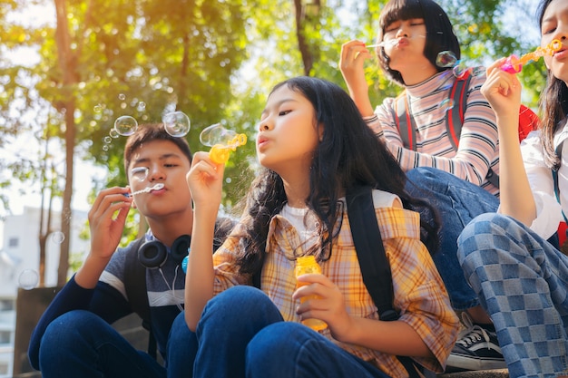 Close up of child blowing soap bubbles and having fun in summer park outdoors