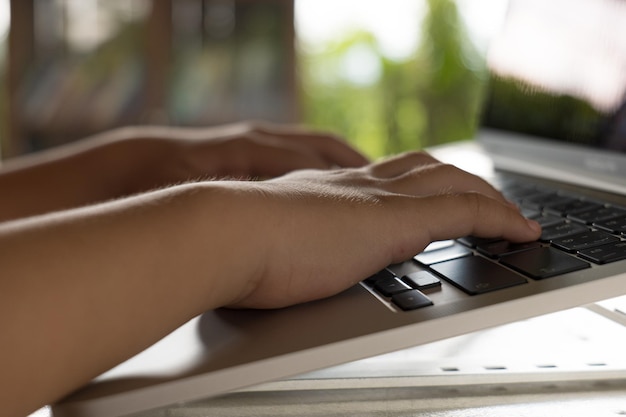 Close up of child hands typing on a laptop computer sitting on a desk at home