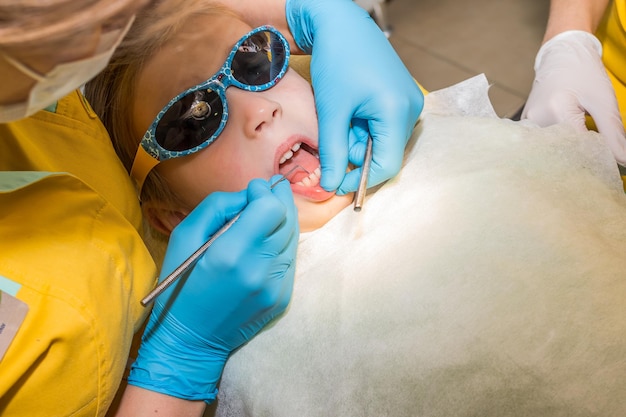 Close up in child mount and checking tooth and by dental mirror tools Dentist checked and curing teeth a child patient in the dental office