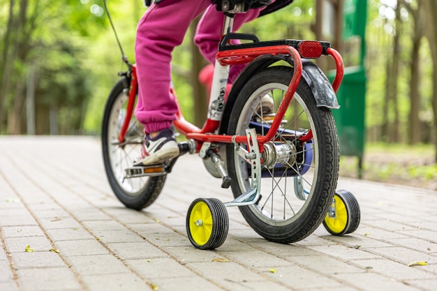 Photo close-up of a child rides a bicycle with three wheels.