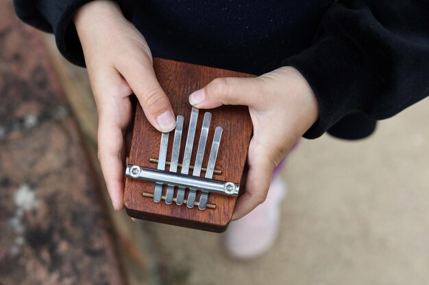 a close up of childs hands playing wooden kalimba musical instrument