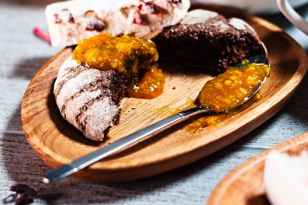 Close up choccolate bisquit with orange marmelade serving on wooden plate on table