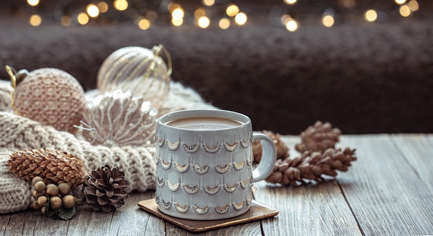 Close up of Christmas cup and festive decor on blurred dark background with bokeh.