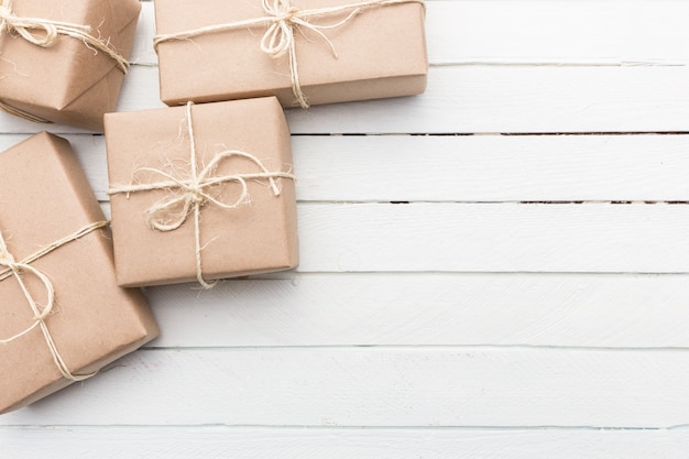 Close up Christmas style rustic brown paper package tied up with strings. White wood background.