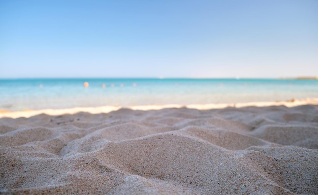 Close up of clean yellow sand surface covering seaside beach with blue sea water on background Travel and vacations concept