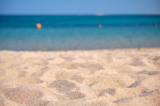 Close up of clean yellow sand surface covering seaside beach with blue sea water on background Travel and vacations concept