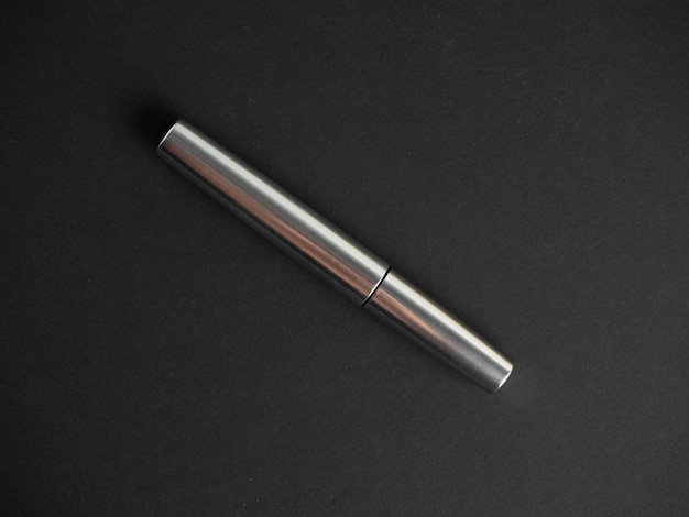 Close-up of a closed mascara of silver color on a black background. The concept of cosmetics for women. top view, flat lay