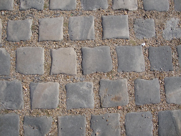 A close up of a cobblestone sidewalk with a rough surface.