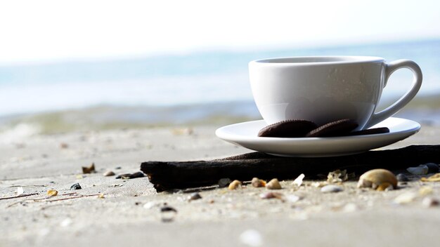 Close-up of coffee cup on beach