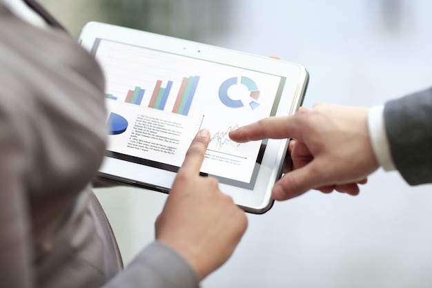 Close up. colleagues discuss financial data using a digital tablet.