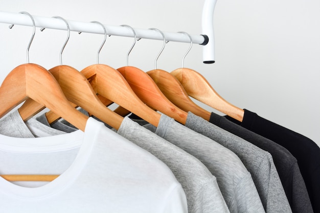 Close up collection of black, gray and white t-shirts hanging on wooden clothes hanger