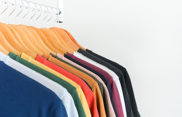 Close-up collection of colorful tshirts hanging on wooden clothes hanger over white background