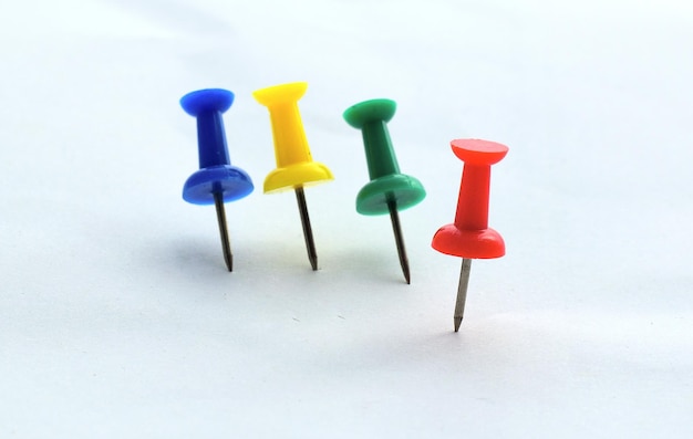 Photo close-up of colored thumbtacks over white background