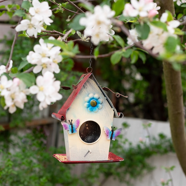 Close-up of a colorful birdhouse on a blurred floral wall