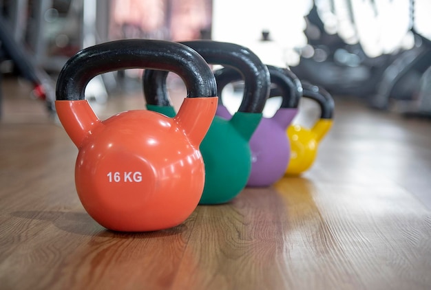 Close-up of colorful kettlebells on hardwood floor