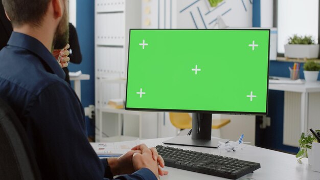 Photo close up of computer with horizontal green screen on desk and colleagues talking about business strategy. workmates working on monitor with isolated background and mockup template.