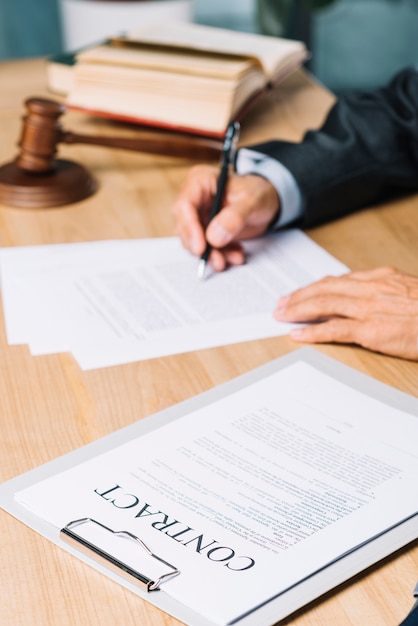 Close-up of contract papers near judge examining documents over desk