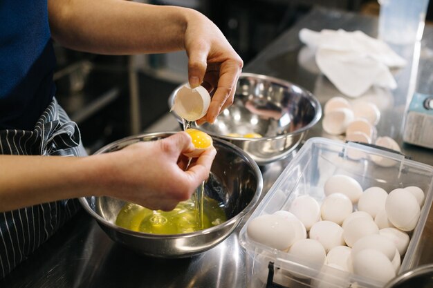 Close up A cook in the kitchen of a cafe or bakery Female hands break eggs for dough