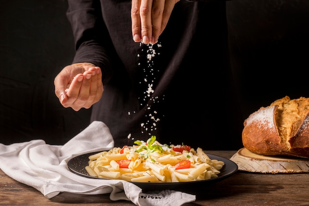 Close-up cook pouring cheese on pasta