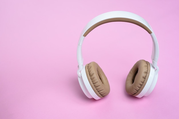 Close-up Cool Wireless headphone against on pink background. Music concept