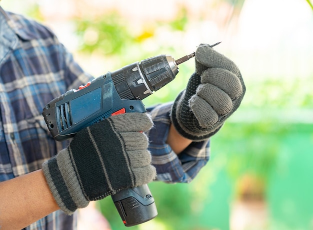 Photo close up cordless screwdriver and screw bolts in the hands of a carpenter