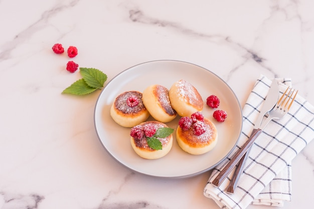 Close up of cottage cheese pancakes with fresh berries on white marble table. Tasty breakfast food. Syrniki