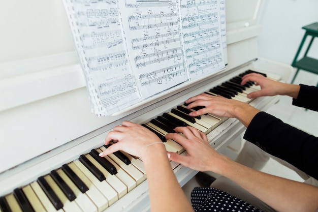 Close-up of couple's hand playing piano with musical sheet