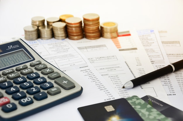 Close up of a credit cards with credit card statements, coins and calculator 