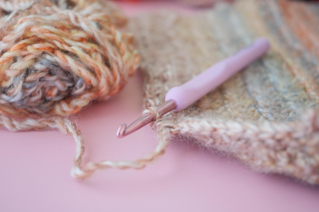 Photo close up of a crochet hook on magenta yarn on pink surface