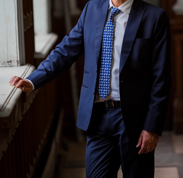 Close-up cropped Caucasian hands and arms of businessman in a suit with blue tie